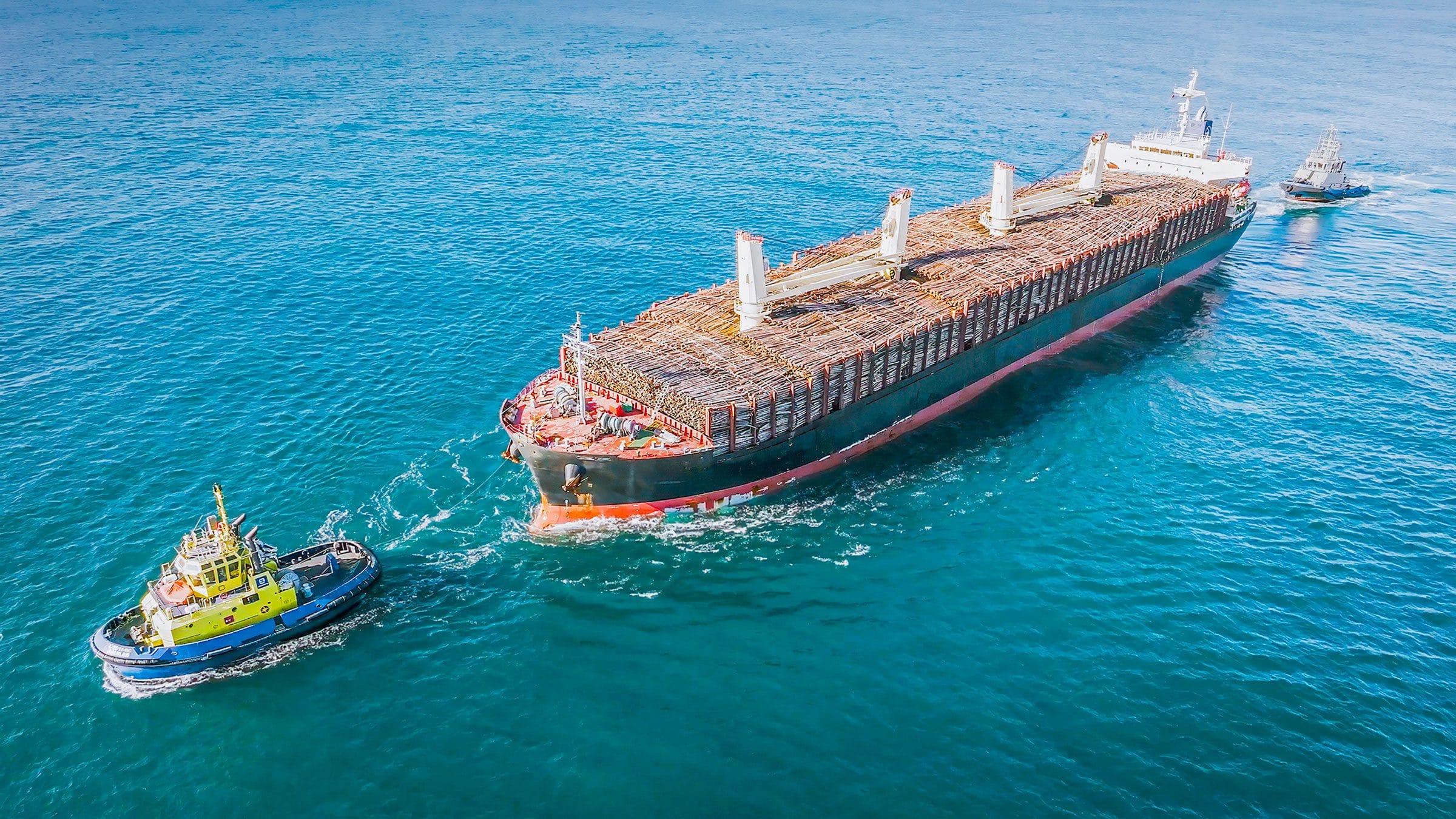 Ship loaded with pulp wood logs from Beira, Mozambique being towed into harbour in Portugal by tug boats.