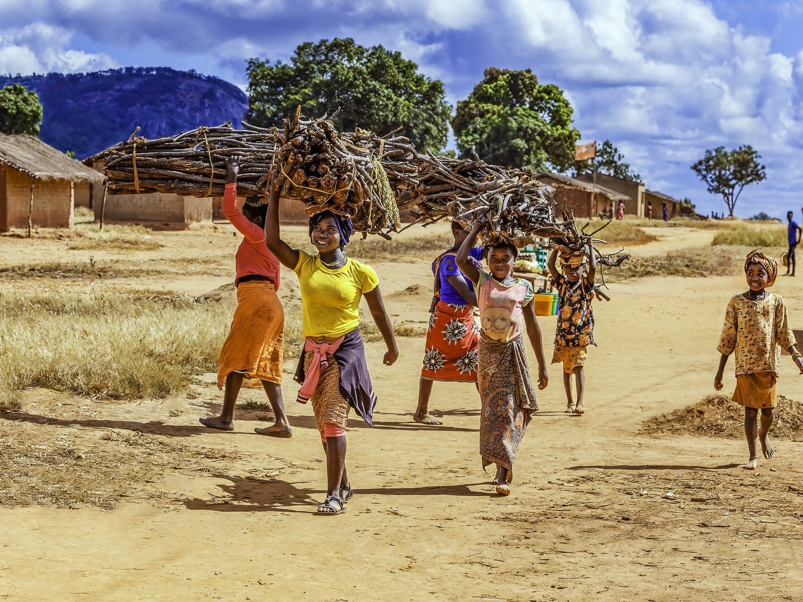 Home CTA Young ladies from a community village carrying firewood on their heads in Mozambique.