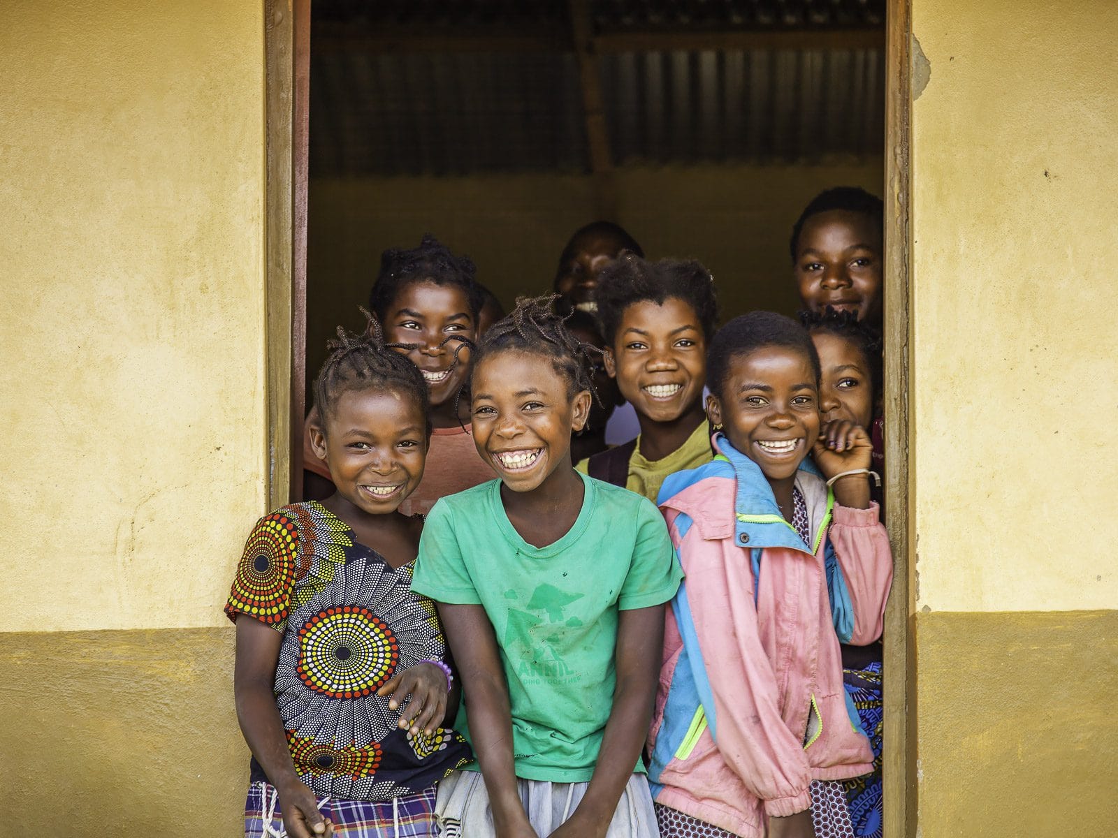 Laughing village children standing in a classroom doorway in Mozambique.